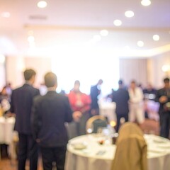 Blurred event scene; people socializing in a bright room