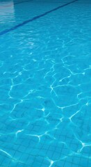 Obraz premium Clear blue swimming pool water with sunlit surface ripples