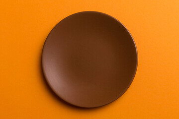 Top view of isolated of colored background empty round brown plate for food. Empty dish with space for your design