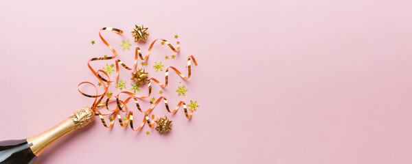 Creative flat lay composition with bottle of champagne and space for text on color background. Champagne bottle with colorful party streamers. holiday or christmas concept