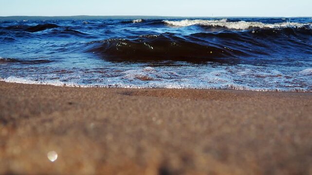 Enjoy sound of waves gently crashing on sandy beach at Lake Onego in Karelia. The serene landscape showcases beauty of natural location. Dark water with high iron content, sand containing shungite