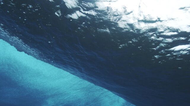 Underwater tracking follows vortex of open ocean wave at Cloudbreak Fiji crashing with foam and whitewash