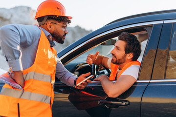 Road construction workers in safety vests and helmets discuss work progress at a construction site