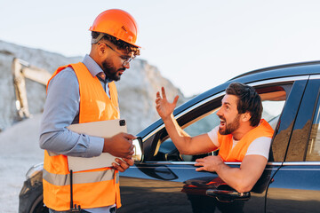 Angry bearded man sitting in modern car yelling at colleague on mining site