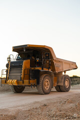 Large mining dump truck standing on dusty quarry road surrounded by rocky terrain