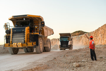 Large mining dump truck standing on a dusty quarry road surrounded by rocky terrain © Maria Vitkovska