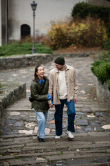 Obraz premium Diverse couple walking up stone stairs holding hands
