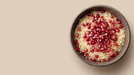 A minimalist pomegranate couscous bowl on matte beige background, overhead shot with copy space