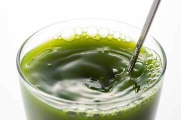 グラスにはいった青汁をまぜる