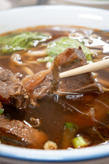 Taiwanese beef noodle soup, famous food in a bowl on wooden table.