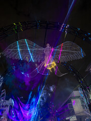 A mesmerizing night scene showcasing a vibrant, ethereal wireframe angel with expansive wings,...