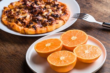 Savory tart and fresh orange halves on wooden table