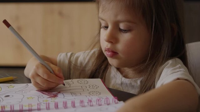 girl engaged in sketching with concentration, young girl diligently coloring her sketchbook