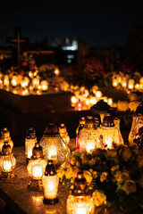 Night scene of a cemetery illuminated by hundreds of candles during All Saints Day. Warm glowing lights, bokeh and flowers creating a peaceful, spiritual atmosphere. Shot in Biały Kościół, Poland.