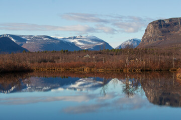 Laukkujärvi lake near Nikkaluokta, Lappland, Northern Sweden, in late autumn, with snow covered mountains reflecting in the water