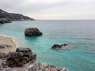 Serene rocky shoreline with turquoise waters under overcast skies