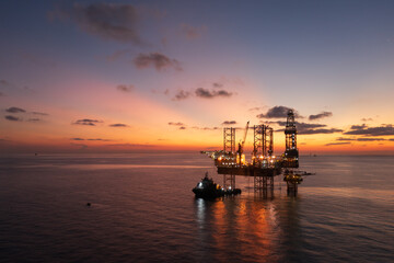 Aerial view of offshore jack up rig and offshore platform during sunset for oil and gas exploration and production.