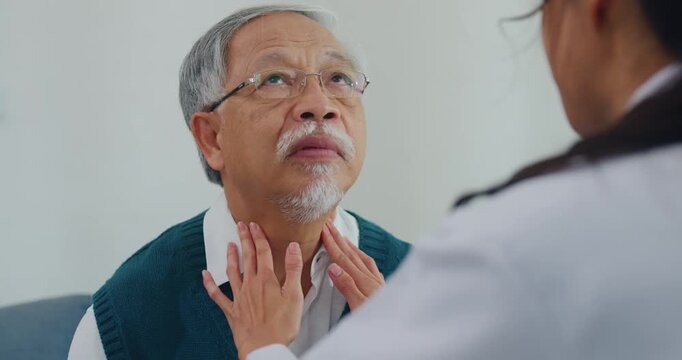 Young Asia female doctor with mature male patient check throat diagnosis and consultation for examination healthcare on sofa in clinic office. Otolaryngologist for thyroid health, pain and infection.