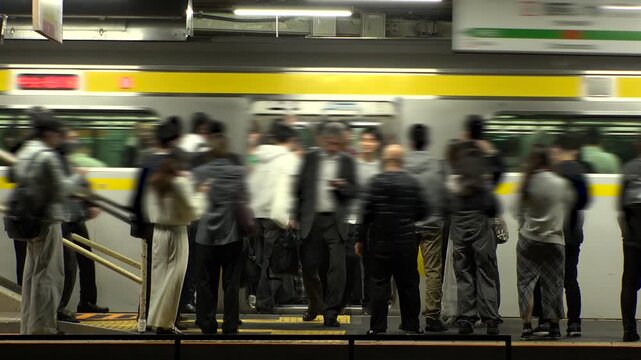 TOKYO, JAPAN - NOV 2025 : View of train station in Tokyo. Crowd of people at the platform in busy night rush hour. Japanese urban city life, transportation, traffic and commute concept video.
