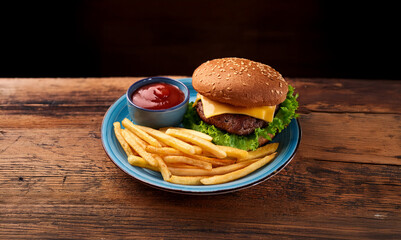 Cheeseburger and french fries on a blue plate. Typical American fast food.