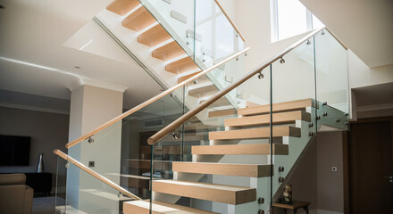 Interior architectural detail of a bright, contemporary staircase with glass railings and light wood steps