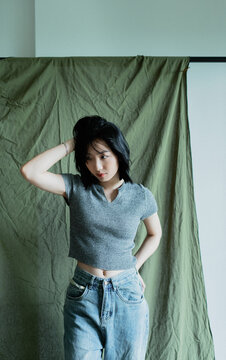 Person poses thoughtfully in modern setting with neutral tones and soft lighting, highlighting casual fashion choices and contemplative mood