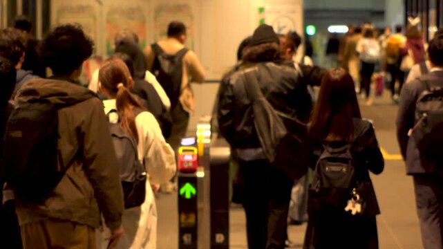 TOKYO, JAPAN - NOV 2025 : Automatic ticket gate at the train station. Crowd of people passing through the gate. Japanese urban city life, transportation, traffic and commute concept slow motion shot..