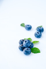 Fresh blueberries with green leaves on a white background. Wild berry close-up, selective focus