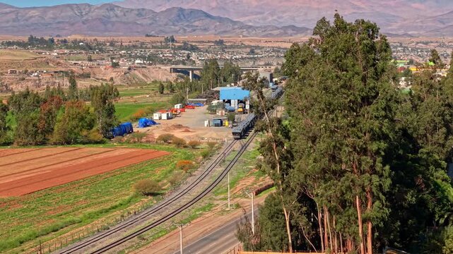 Aerial fly Ferronor Railway in Vallenar, Huasco Valley Chile, Old Industrial Train Tracks Below Andean Mountains