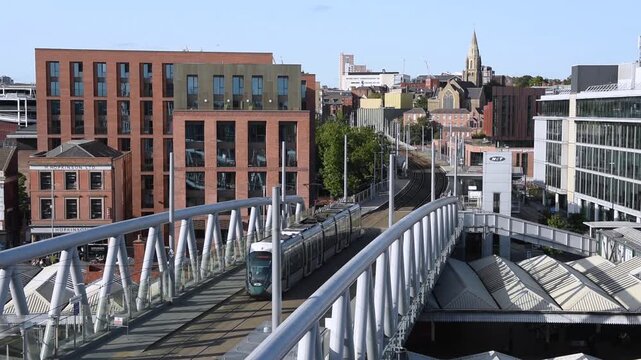 Overlooking the Nottingham tram passing by Nottingham Station with the city skyline in the background. This urban scene captures public transport and the cityscape of Nottingham, England.