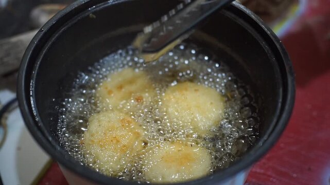 Traditional Indonesian snack combro being deep-fried in an electric fryer until golden and crispy.
