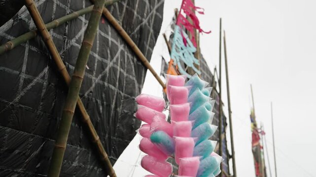 Pink and blue cotton candy displayed beside giant kites at Sumpango festival