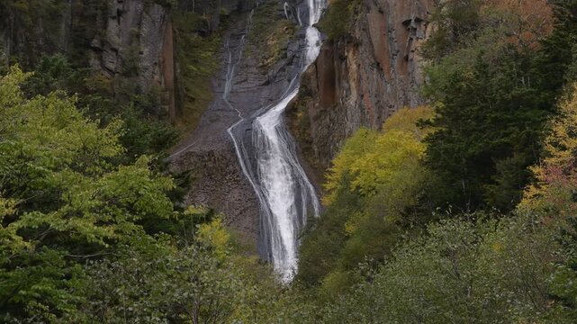 Close-up of Ginga waterfall surrounded by colourful autumn trees, a popular tourist landmark at Sounkyo, Daisetsuzan National Park, Hokkaido, Japan.