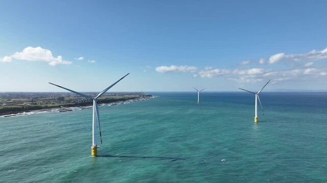 冬が近く風の強い富山湾沿岸の洋上風力発電風車や波のかかる離岸堤などの風景