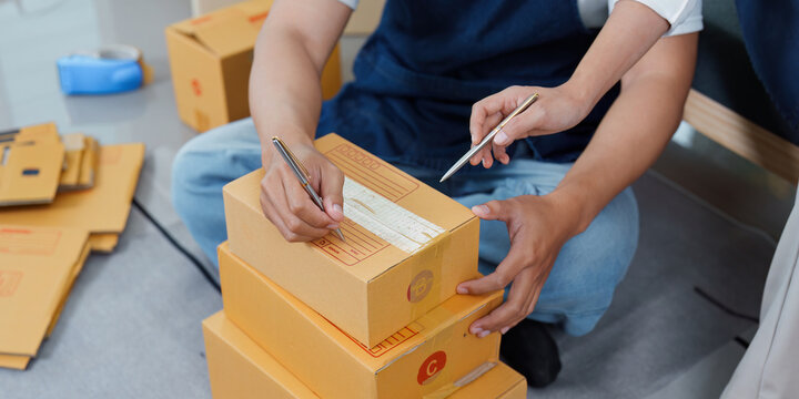 Teamwork in logistics. Two workers labeling boxes in a warehouse. - Powered by Adobe
