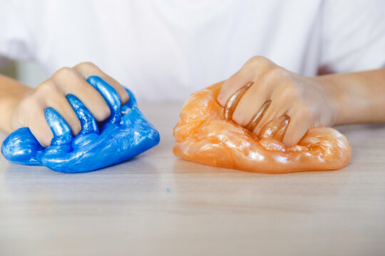 A cheerful boy plays with slime.