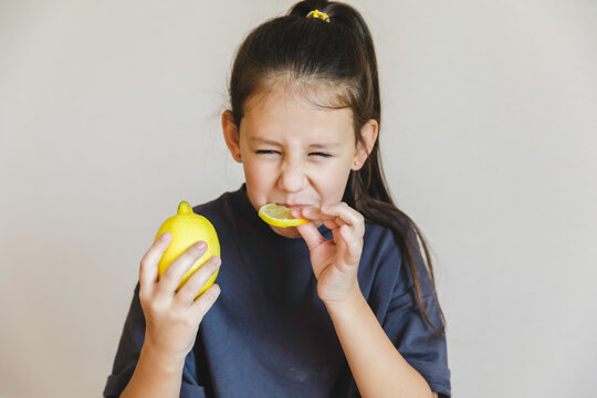 Cute little girl eating fresh lemon isolated on white background