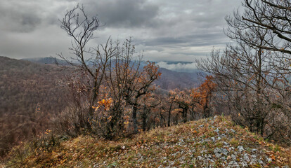 Panoramic view of forested hills and drifting fog below Gerenna Castle ridge in the Bükk Mountains on a cloudy day.