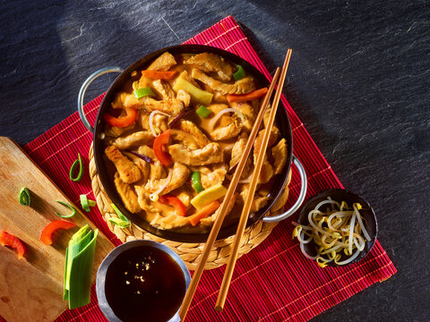 Putengeschnetzeltes Teriyaki mit Staebchen Paprika und Sojasauce auf roter Bastmatte, asiatisch, Wokgericht, Pute, Gefl&uuml;gel, Gem&uuml;se, 
