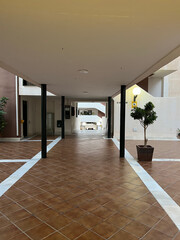 A residential courtyard with a brown ceramic tile floor and potted plants. Spain, 2022.