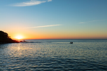 Sunrise on the beach with boat in Balne&aacute;rio Cambori&uacute; with a peninsula in the background in the state of Santa Catarina, Brazil.