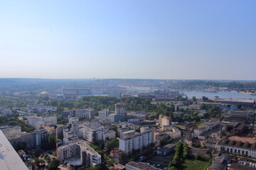 Fototapeta premium Panoramic view of industrial city with port and cranes on summer day