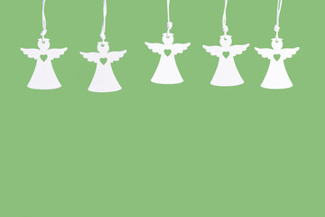 Flat wooden angel figures on green surface, festive decoration layout.