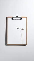 White paper on clipboard with small flower, neutral light