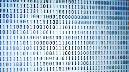 Closeup of a computer screen displaying a continuous stream of binary code representing digital data programming and the abstract concept of information technology in a modern hightech environment. - Powered by Adobe