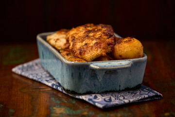Fried chicken breast with potatoes. Rustic wooden background. Soft focus.	