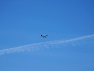 Contrail of an airliner and a small aircraft in the blue sky. Symbol of aviation. Copyspace.