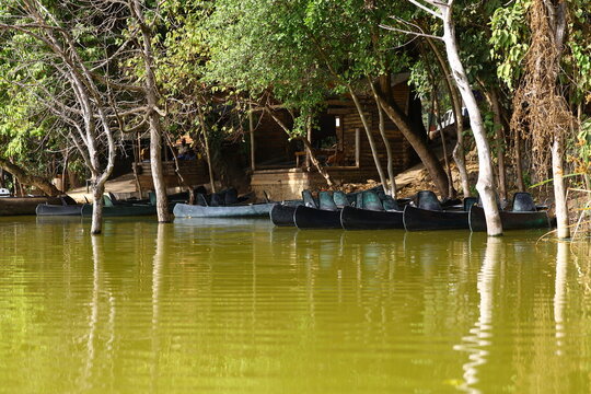 Empty canoes by the pier on green rippling water of Lake Duluti with small wooden ticket hut for tourists — Tanzania