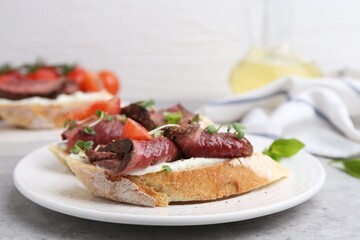 Delicious bruschettas with roast beef served on light table, closeup. Space for text