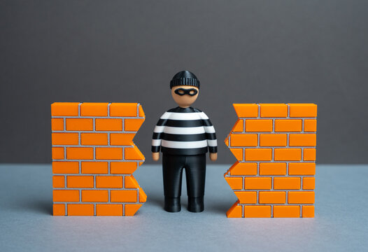 A criminal finds a hole in the wall. A breach in security. The threat of data theft and cybersecurity. System vulnerability and unauthorized access. Hacking risks, corporate espionage